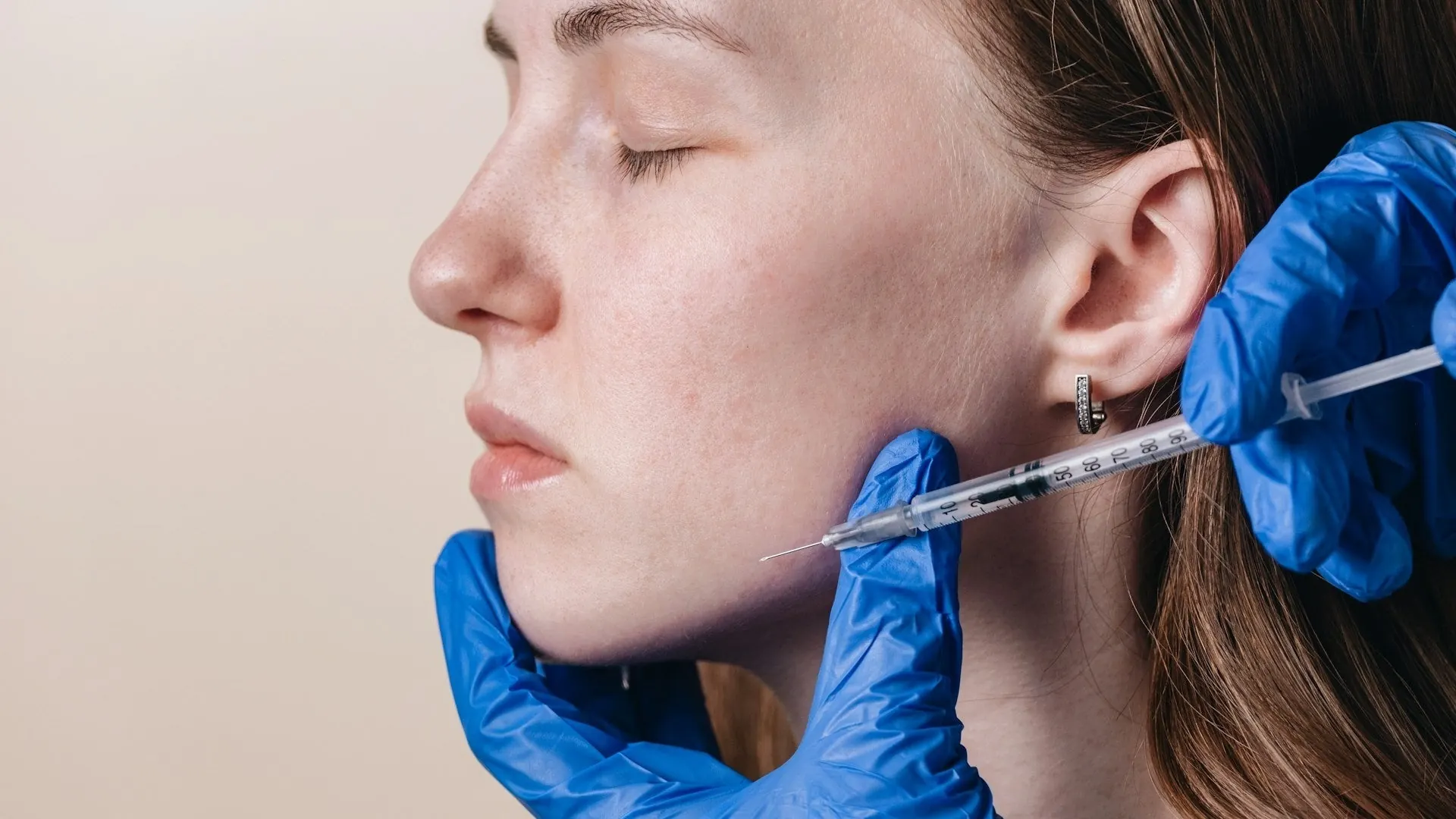 Woman having a jaw slimming treatment at the jaw muscle