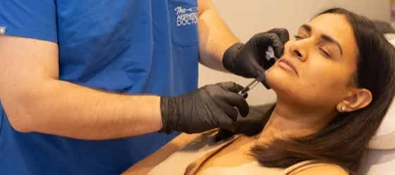Practitioner injecting a collagen stimulator into a patient’s jawline